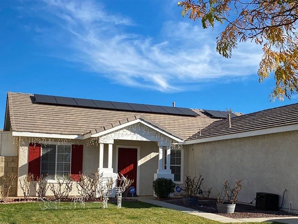 Completed residential solar install seen from the street, black panels on a tile roof