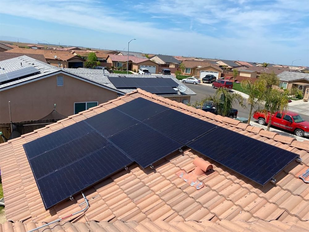Solar array fitted around the hips of a terracotta tile roof in a residential neighbourhood